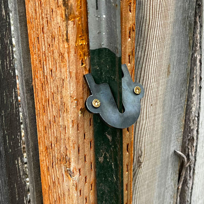 close-up of a fence repair bracket that attaches a metal t-post to a wooden fence